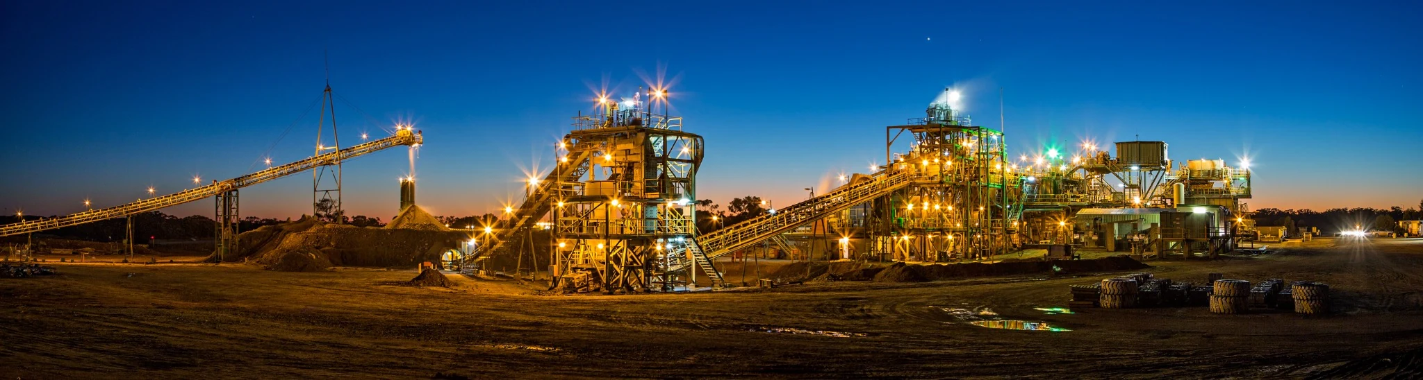 Mineral-processing plant and conveyors illuminated at dusk